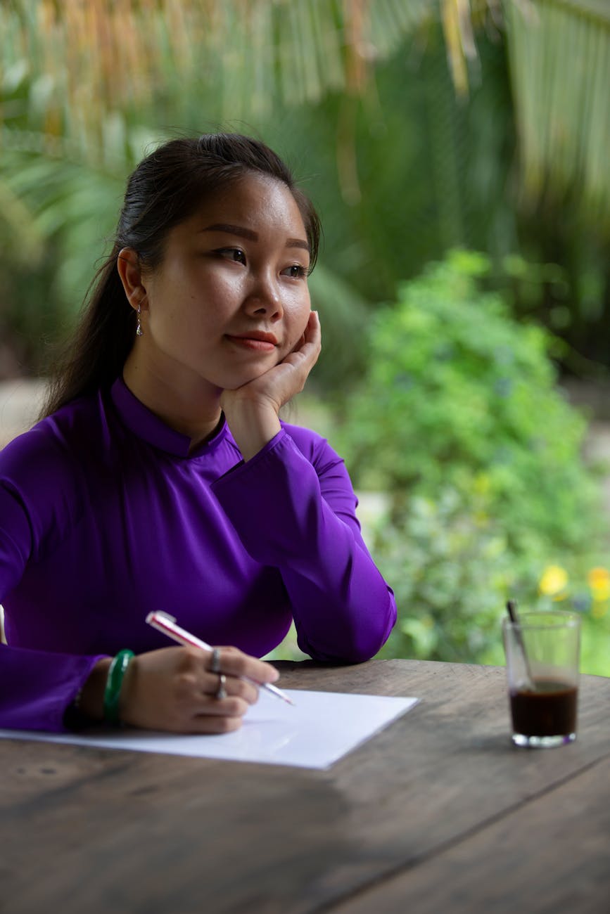 woman in purple long sleeves pondering on what to write